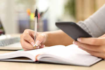 Woman hand writing in agenda consulting phone