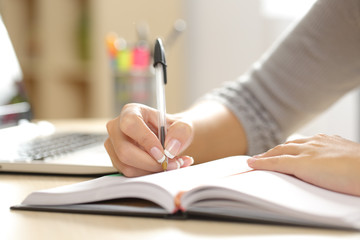 Woman hand writing in an agenda at home