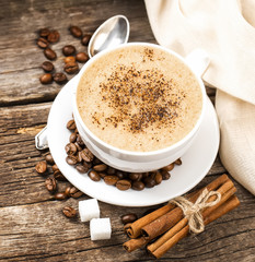 Close-up of coffee cup with roasted coffee beans on wooden backg