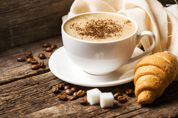 Close-up of coffee cup with roasted coffee beans on wooden backg