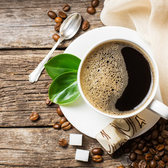 Close-up of coffee cup with roasted coffee beans on wooden backg