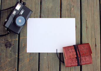 Camera, white paper and notebook on a wood table