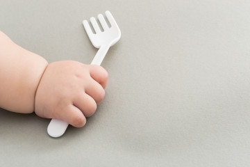  White fork in hand of newborn baby .