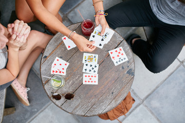 Three young friends playing cards at cafe