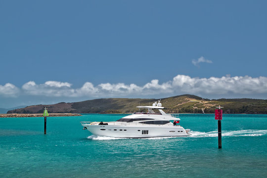 A luxury cruiser navigates through channel markers to enter the Hamilton Island marina, Australia.