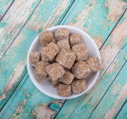 Sugarcane sugar cube in white bowl over wooden background