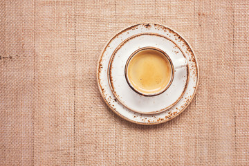 Cup of coffee on burlap background. Top view, toned,  copy space
