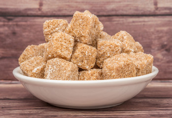 Sugarcane sugar cube in white bowl over wooden background