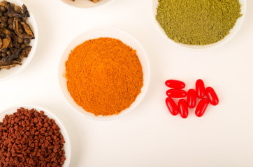 Beautiful colorful display of different spices green orange brown in white bowls, shot from above angle, bright background