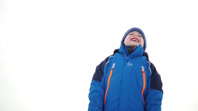 4k footage, happy young boy in winter clothes throwing snow in the air and smiling

