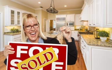 Young Woman Holding Sold Sign and Keys Inside New Kitchen