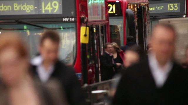 People walking with double decker red buses near the London Bridge, England.