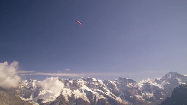 Long distance shot of a paraglider hovering above the Swiss alps