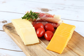 cheese and prosciutto on a wooden board