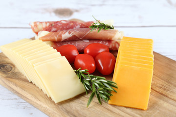 cheese and prosciutto on a wooden board