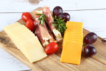 cheese and prosciutto on a wooden board