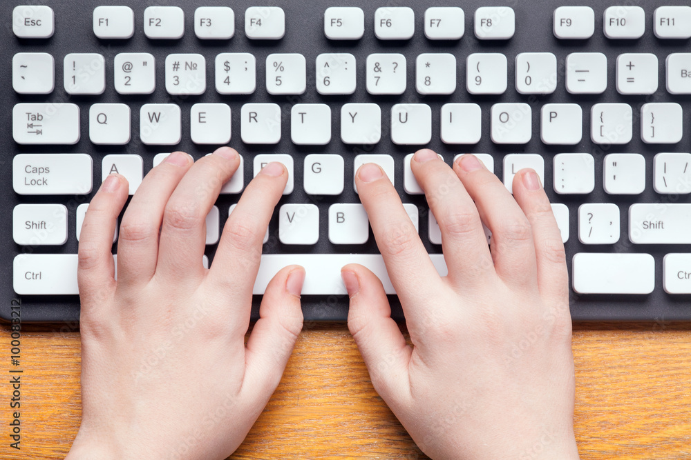 Wall mural top view of hands typing on computer keyboard
