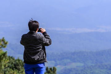 Fototapeta premium Man hiker take a photo of mountain view with smartphone.