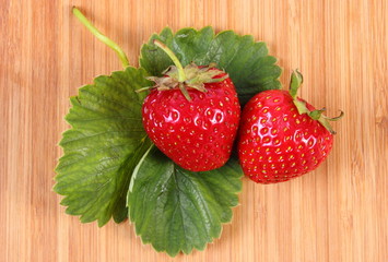 Strawberry with leaves on wooden surface