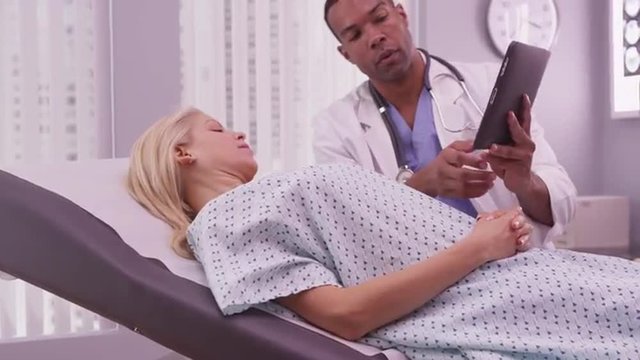 Black doctor sharing woman patient's xray on tablet