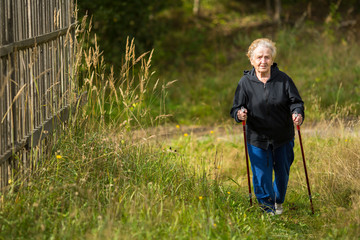 An elderly woman practices Nordic walking in the Park.