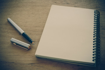 paper notebook and pen on a table with filter effect retro vinta