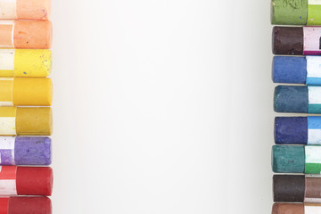 Set pastel art on a white background. Pastel pencils are located along the right and left sides of the frame