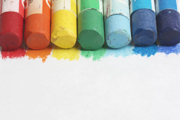 Set pastel art on a white background. Colors of rainbow. Pastel pencils are located along the upper side of the frame