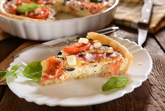 Tart (Quiche) with tomatoes, basil, salami, black olives and che