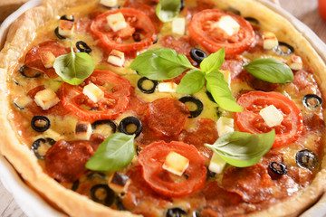 Tart (Quiche) with tomatoes, basil, salami, black olives and che