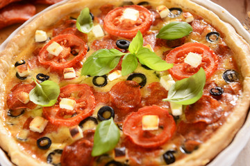 Tart (Quiche) with tomatoes, basil, salami, black olives and che