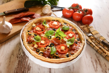 Tart (Quiche) with tomatoes, basil, salami, black olives and che