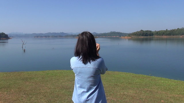 Young woman Takes Picture of Forest Mountain a beautiful view by the lake