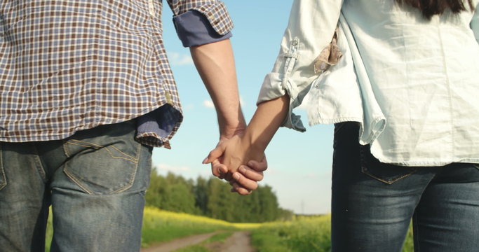 Close-up of couple walking in countryside and holding hands