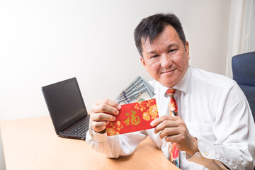 Employee displaying red packet with Good Fortune Chinese character, and money received during Chinese New Year in office