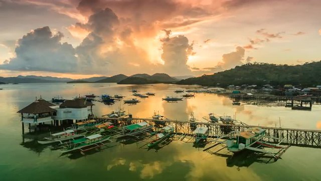 Sunset over Coron harbour timelapse, Coron, Palawan, Philippines. View on pier with traditional bangka boats