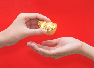Hand giving gold ingot to someone for Chinese New Year celebrat