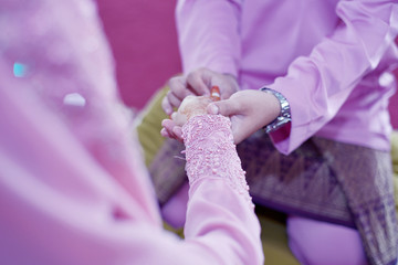 Malay Wedding Couple Putting A Gold Ring On Hand.Selective Focus