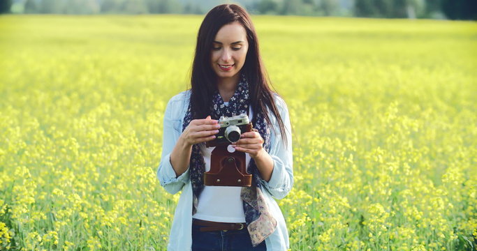 Pretty lady taking a picture with camera in the meadow and smiling