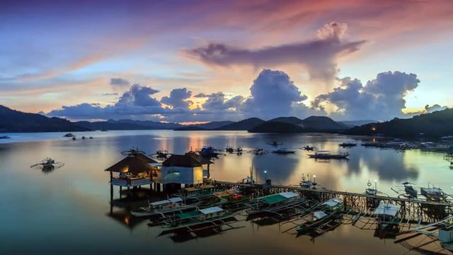 Sunset over Coron harbour timelapse, Coron, Palawan, Philippines. View on pier with traditional bangka boats