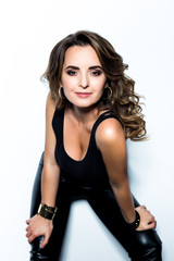 Fototapeta premium Beautiful Woman with Curly Hair dressed in a black T-shirt and leather pants in white background