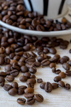 Detial view of coffee beans with coffee cup in background.