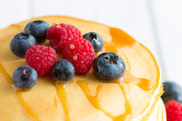 Stack of Sweet Pancakes with Fresh Blueberry, Raspberry, Apple and Maple Syrup on White Light Background