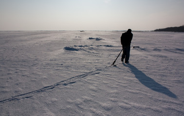 hunched man drags the anchor along the ice
