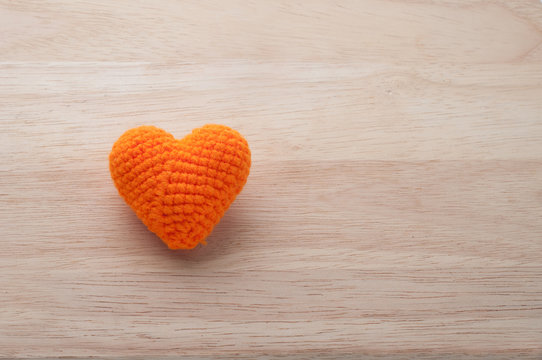 Knitted fabrics heart shape on wooden background, valentine day