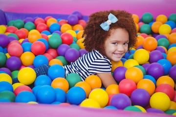 Fototapeta na wymiar Cute smiling girl in sponge ball pool