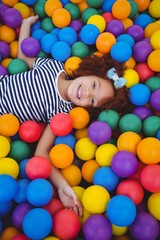 Fototapeta na wymiar Cute smiling girl in sponge ball pool