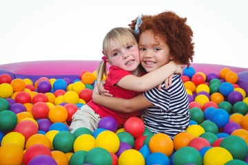 Fototapeta na wymiar Cute smiling girls in sponge ball pool hugging