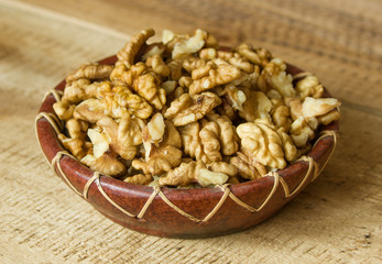 The plate with walnuts on the wooden background
