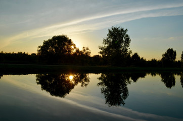 Sunset, cloud formation and trees reflecting in water